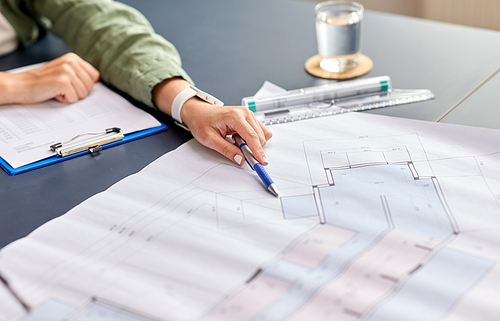 construction business, architecture and building concept - close up of architect with blueprint, clipboard and pen working at office