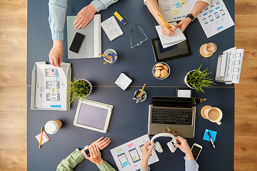 business, people and team work concept - team of startuppers with gadgets and papers working at office table