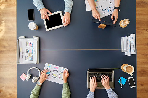 business, people and team work concept - team of startuppers with gadgets and papers working at office table