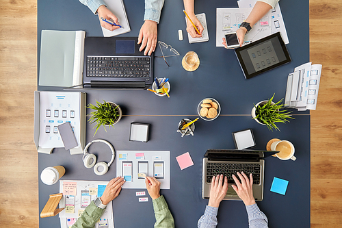 business, people and team work concept - team of startuppers with gadgets and papers working at office table