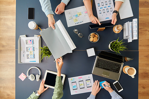 business, people and team work concept - team of startuppers with gadgets and papers working at office table