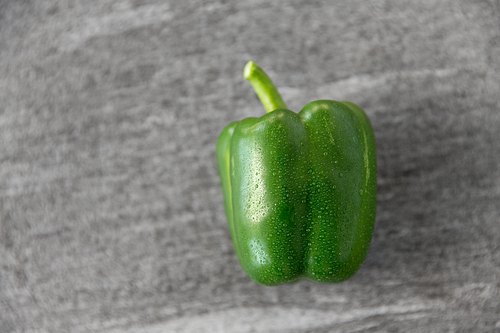vegetable, food and culinary concept - close up of green pepper on slate stone background