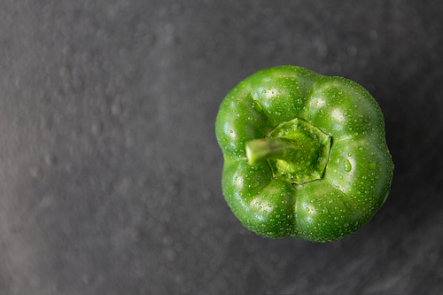 vegetable, food and culinary concept - close up of green pepper on slate stone background