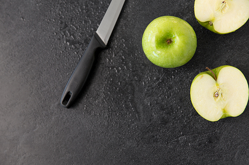fruits, diet,  food and objects concept - green apples and kitchen knife on slate stone background