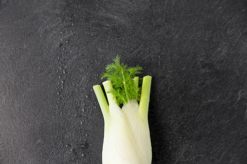 vegetable, food and culinary concept - close up of fennel on slate stone background