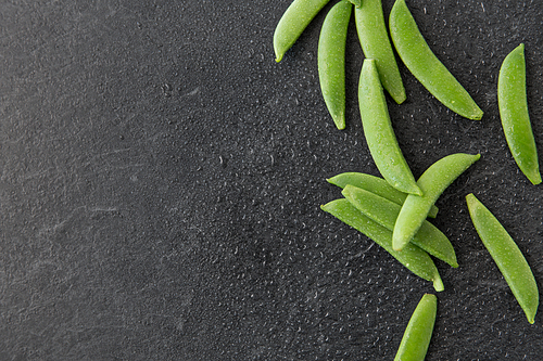 vegetable, food and culinary concept - peas on wet slate stone background