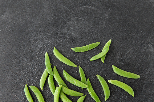 vegetable, food and culinary concept - peas on wet slate stone background