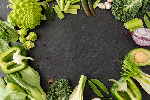 food, culinary and healthy eating concept - close up of different green vegetables and fruits on slate stone background