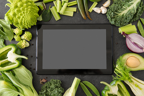 food, diet and healthy eating concept - close up of different green vegetables and tablet pc computer with blank screen on slate stone background