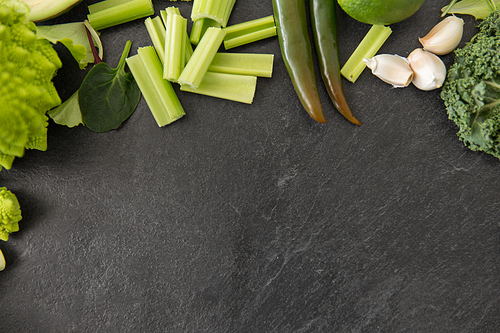 food, culinary and healthy eating concept - close up of different green vegetables on slate stone background