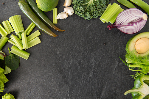 food, culinary and healthy eating concept - close up of different green vegetables and fruits on slate stone background