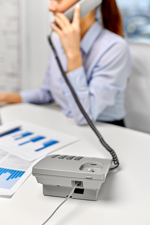 business, communication and people concept - businesswoman with computer and papers calling on desk phone at office