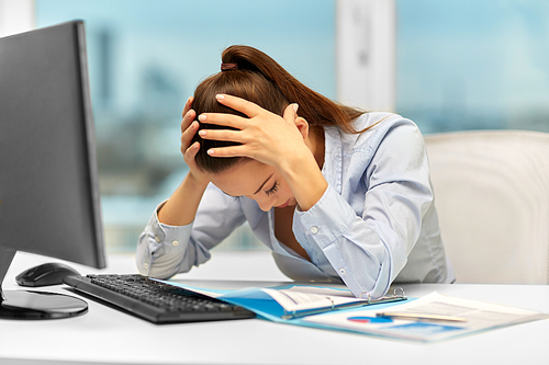 business, people and failure concept - stressed businesswoman with papers and computer holding to head at office