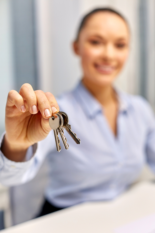 real estate business and people concept - close up of businesswoman or realtor holding keys at office