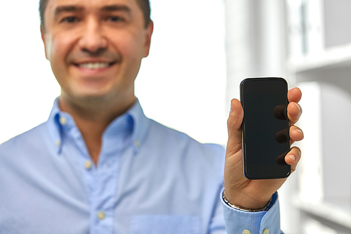 business, people and technology concept - close up of happy smiling businessman showing smartphone black blank screen