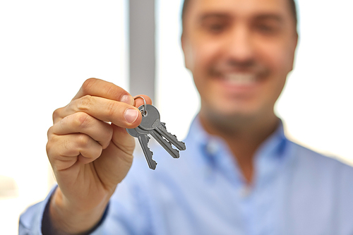 real estate, housing and people concept - close up of smiling man holding house keys