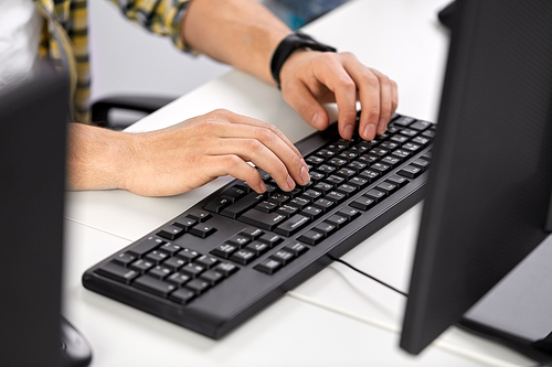 technology and people concept - male hands with red manicure typing on computer keyboard on table