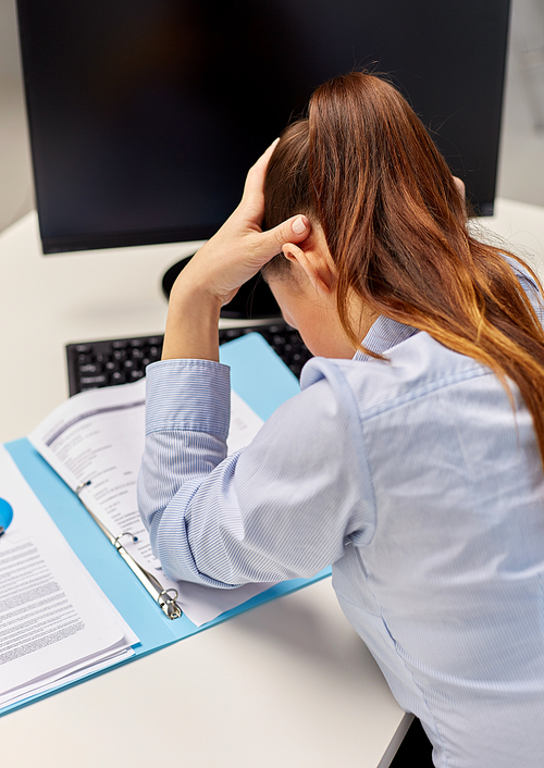 business, people and failure concept - stressed businesswoman with papers and computer holding to head at office