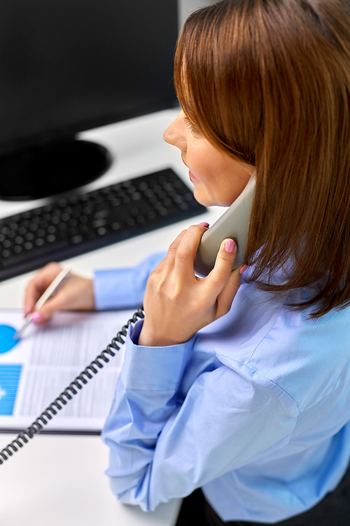 business, communication and people concept - businesswoman with computer and papers calling on desk phone at office