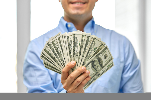 business, people and finances concept - close up of smiling businessman with american dollar money