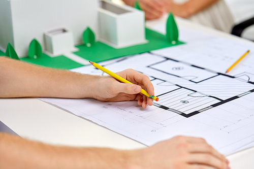 architecture, construction and people concept - team of architects or designers with project blueprint and building layout working at office