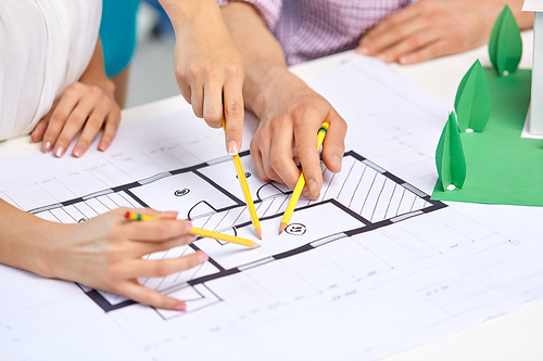 architecture, construction and people concept - team of architects or designers with project blueprint and building layout working at office