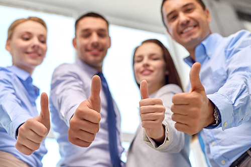 success, people and gesture concept - close up of happy smiling business team showing thumbs up sitting at table in office