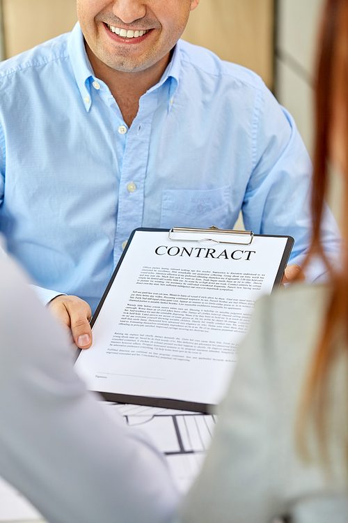 real estate business, sale and people concept - happy smiling male realtor with blueprint showing contract document to customers at office