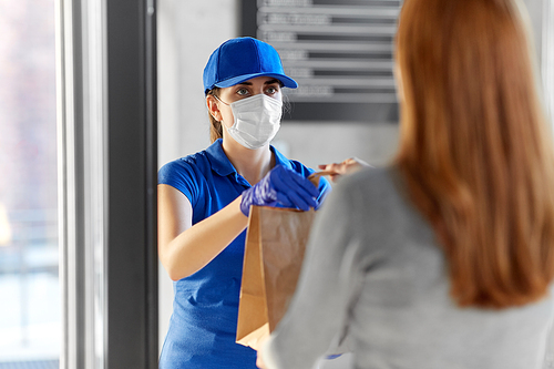 health protection, safety and pandemic concept - delivery woman in protective face mask and gloves giving paper bag with food to female customer at office
