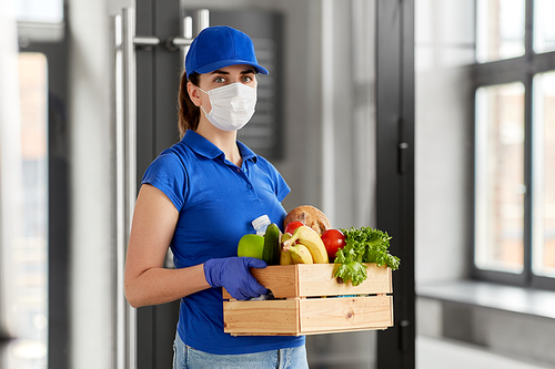 health protection, safety and pandemic concept - delivery woman in face mask and gloves holding wooden box with food