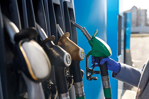 health, safety and pandemic concept - close up of hand in glove gasoline nozzle at gas station