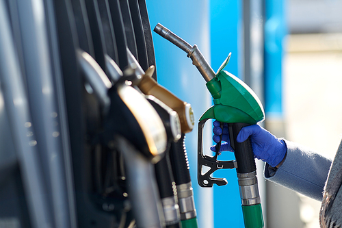 health, safety and pandemic concept - close up of hand in glove gasoline nozzle at gas station