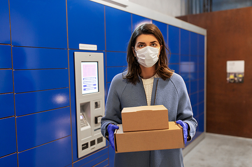 health care, mail delivery and pandemic concept - woman wearing face protective medical mask for protection from virus disease with boxes at automated parcel machine