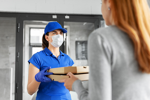 health protection, safety and pandemic concept - delivery woman in medical face mask and gloves giving pizza boxes to female customer at office