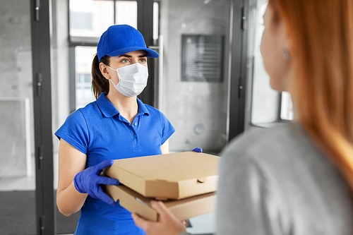 health protection, safety and pandemic concept - delivery woman in medical face mask and gloves giving pizza boxes to female customer at office