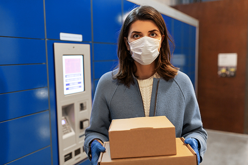 health care,  delivery and pandemic concept - woman wearing face protective medical mask for protection from virus disease with boxes at automated parcel machine