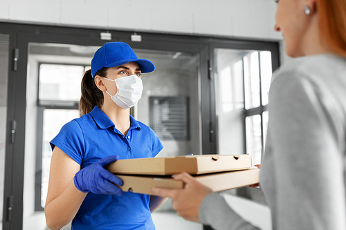 health protection, safety and pandemic concept - delivery woman in medical face mask and gloves giving pizza boxes to female customer at office