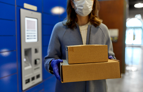 health care,  delivery and pandemic concept - close up of woman wearing face protective medical mask for protection from virus disease with boxes at automated parcel machine