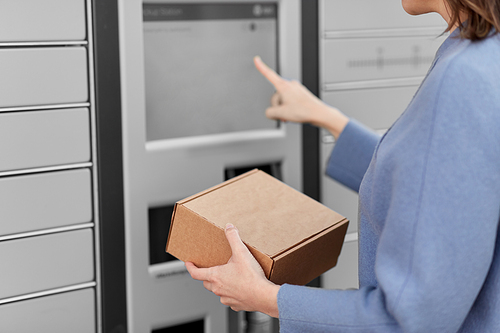delivery and post service concept - close up of happy smiling woman with box at outdoor automated parcel machine choosing operation on touch screen