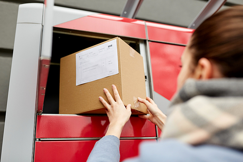 delivery and post service concept - woman putting box to automated parcel machine