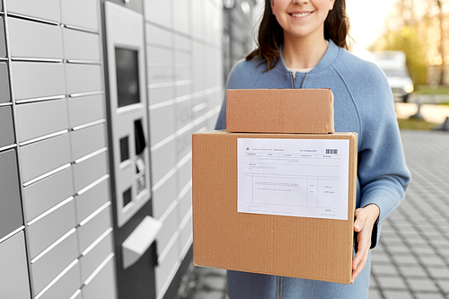 mail delivery and post service concept - close up of happy smiling woman with boxes at outdoor automated parcel machine