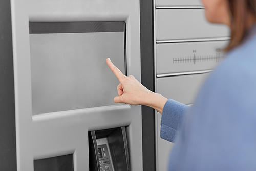 delivery and post service concept - close up of woman choosing operation on outdoor automated parcel machine's touch screen