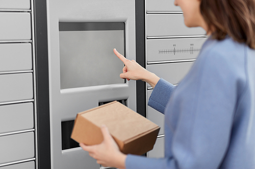delivery and post service concept - close up of happy smiling woman with box at outdoor automated parcel machine choosing operation on touch screen