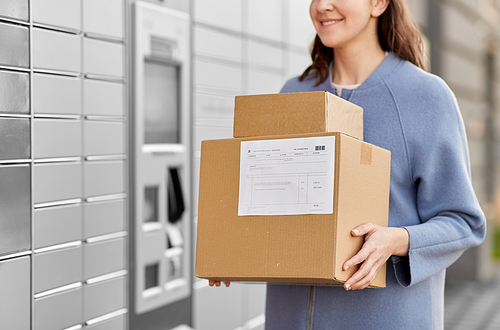 delivery and post service concept - close up of happy smiling woman with boxes at outdoor automated parcel machine