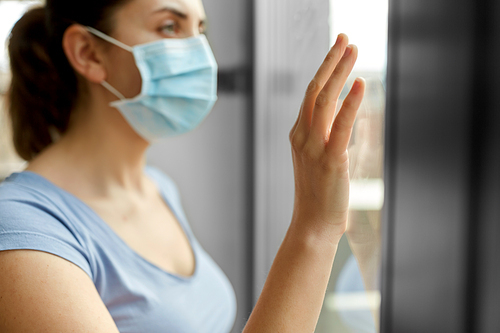 health, safety and pandemic concept - close up of sick young woman wearing protective medical mask looking through window at home