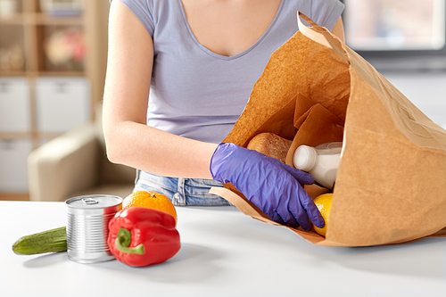 health protection, safety and pandemic concept - close up of woman in protective medical gloves taking food from paper bag at home
