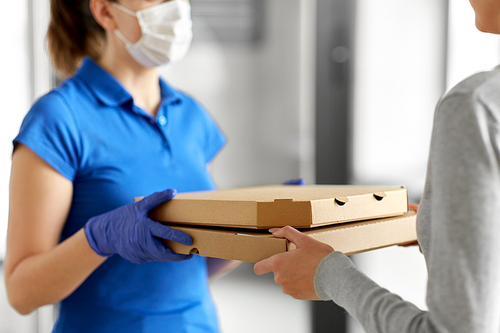 health protection, safety and pandemic concept - delivery woman in medical face mask and gloves giving pizza boxes to female customer at office
