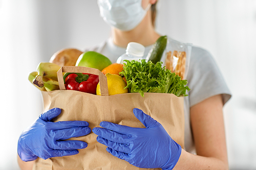 health protection, safety and pandemic concept - close up of woman in protective medical gloves and mask holding food in paper bag at home