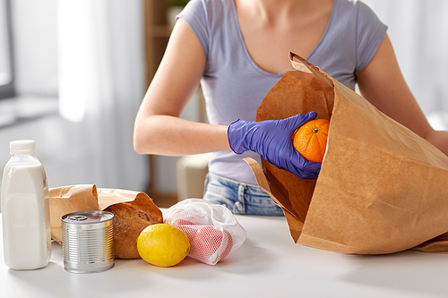 health protection, safety and pandemic concept - close up of woman in protective medical gloves taking food from paper bag at home