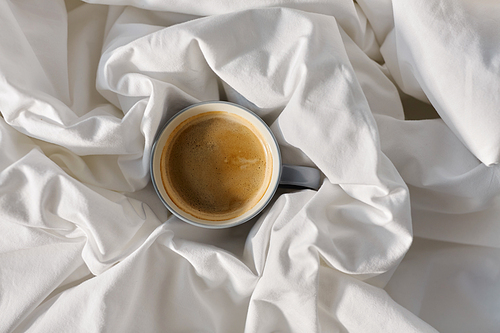 morning, hygge and drink concept - cup of coffee in bed at home